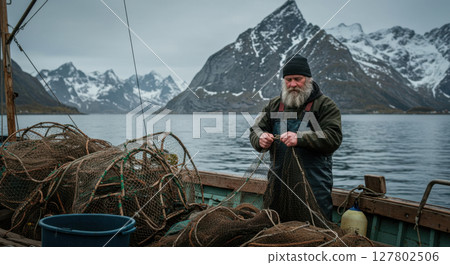 Nordic Fisherman Mending Nets on a Boat with Snowy Mountain Backdrop in Norway 127802506