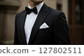 Close-Up of Elegant Man Wearing Black Tuxedo with Bow Tie and Pocket Square Outdoors 127802511