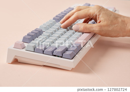 Womans hand typing on mechanical keyboard on pink background. Close up. 127802724