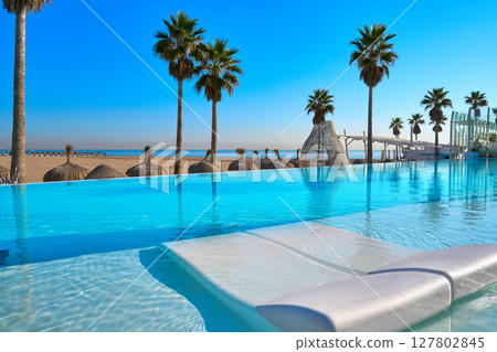 Resort infinity pool in a beach with palm trees 127802845