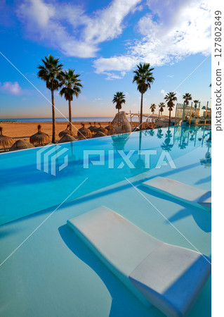 Resort infinity pool in a beach with palm trees 127802849