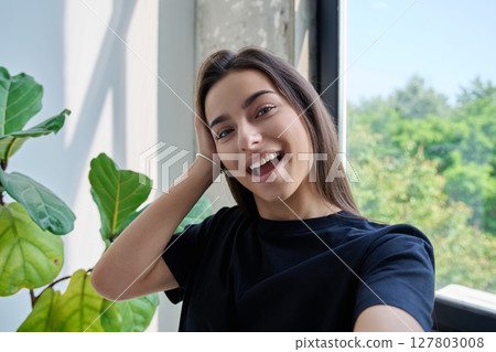 Close-up selfie portrait of teenage female looking at web camera 127803008
