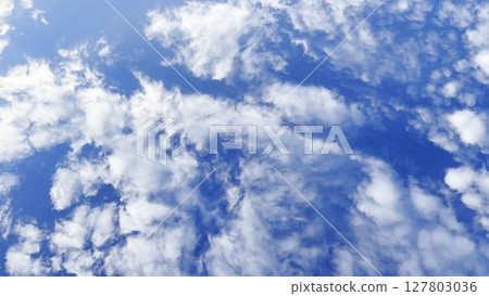 Camera move behind white fluffy clouds on blue sky at summer sunny day. Beautiful nature background. Close up Slow motion 127803036