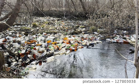Dirty river is polluted with many plastic bottles. A lot of trash is dumped in open and freely available places at nature. Global environmental pollution problem. Concept of ecological disaster 127803038