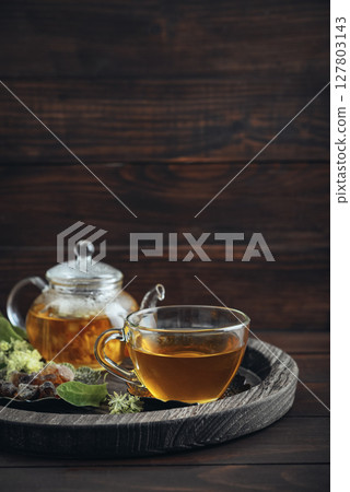 Glass cup of linden tea with glass teapot 127803143