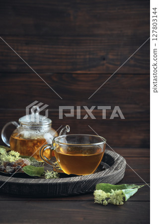 Glass cup of linden tea with glass teapot 127803144