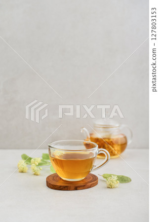 Glass cup of linden tea with glass teapot 127803153