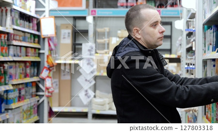 Hardware store employee browsing shelves, comparing tools and supplies, highlighting retail shopping experience and consumer decision making process Hardware store employee browsing shelves, comparing tools and supplies, highlighting retail shopping experience and consumer decision making process 127803318