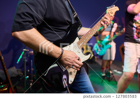 An Energetic and Enthralling Guitar Performance by Trendy Musicians on a Vibrant Stage 127803583