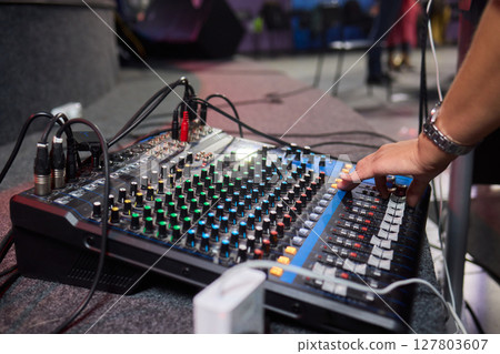 Closeup image of a hand mixing sounds on a control board, showcasing an audio technicians work 127803607