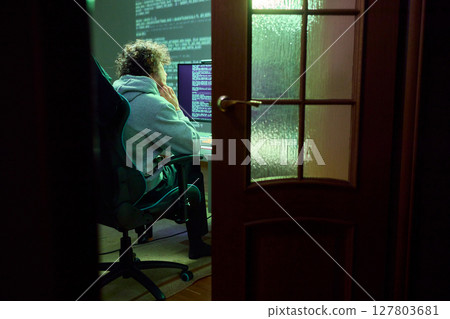 A young programmer codes intently in a dark setting, immersed in his work and creativity 127803681