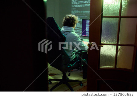 A young programmer codes intently in a dark setting, immersed in his work and creativity A young programmer codes intently in a dark setting, immersed in his work and creativity 127803682