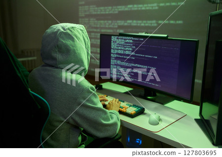 A young programmer codes intently in a dark setting, immersed in his work and creativity A young programmer codes intently in a dark setting, immersed in his work and creativity 127803695