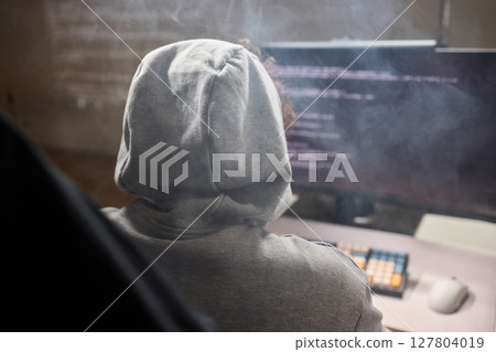 A young programmer codes intently in a dark setting, immersed in his work and creativity 127804019