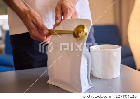 Pouring freshly ground coffee beans into a measuring cup for a perfect morning brew Pouring freshly ground coffee beans into a measuring cup for a perfect morning brew 127804126