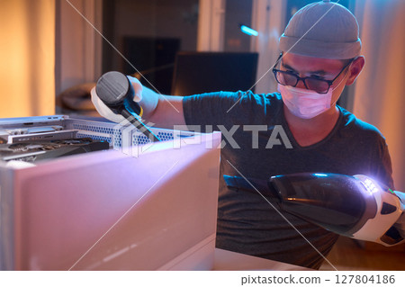 A man cleans a computer case with a vacuum in a bright room, stressing workspace tidiness A man cleans a computer case with a vacuum in a bright room, stressing workspace tidiness 127804186