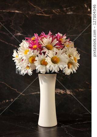 Still life with beautiful daisy flowers in vase on elegant modern background, spring and summer product advertising banner, abstract floral arrangement, holiday greeting card with space for text Still life with beautiful daisy flowers in vase on elegant modern background, spring and summer product advertising banner, abstract floral arrangement, holiday greeting card with space for text 127804346