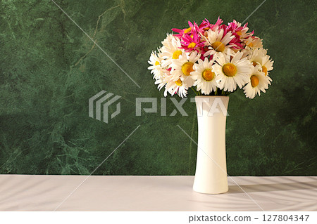 Bouquet of beautiful flowers of garden chamomile and mallow in vase on sunny background, advertising banner of spring and summer products, abstract floral arrangement, holiday card with place for text 127804347