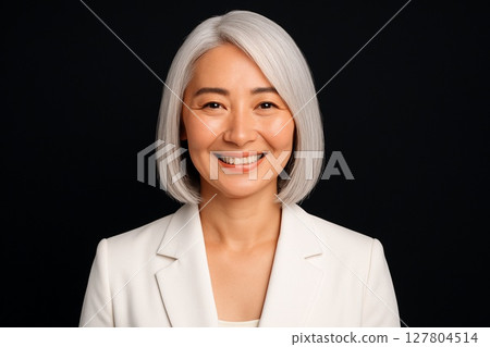 一位白髮中年婦女在黑色背景下微笑的肖像 127804514