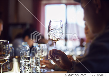 Man Swirling White Wine Glass at Sommelier School 127805012