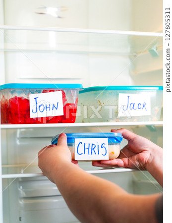 Meal containers labeled with employee names in clean office refrigerator. Lunch time for office workers. Meal containers labeled with employee names in clean office refrigerator. Lunch time for office workers. 127805311