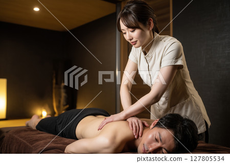 Men's beauty material. A young female staff member massaging a man's shoulders at a men's beauty salon 127805534