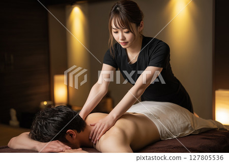男士美容院裡，一位年輕女員工正在為一位男士按摩肩膀 127805536