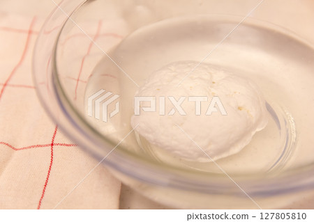 Homemade mozzarella cheese in a glass bowl of water Homemade mozzarella cheese in a glass bowl of water 127805810