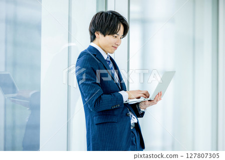 Young businessman with a laptop in the office Young businessman with a laptop in the office 127807305