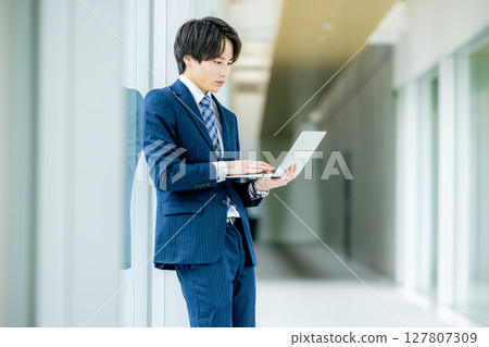 有一台膝上型計算機的年輕商人在辦公室 127807309