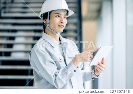 穿著工作服的年輕工人站在辦公室走廊裡 127807348