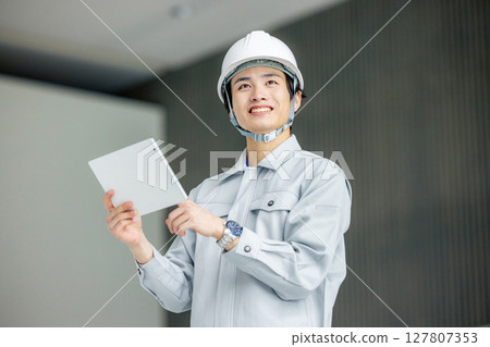 穿著工作服的年輕工人站在辦公室走廊裡 127807353