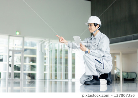 穿著工作服的年輕工人站在辦公室走廊裡 127807356