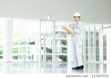 Young worker in work clothes standing in the office corridor Young worker in work clothes standing in the office corridor 127807359