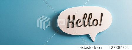 White speech bubble with the word hello written in black letters represents communication, greeting, and online chatting on a vibrant blue background 127807704