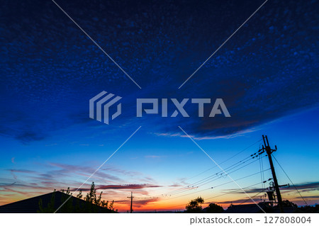 Beautiful sunset after the rain. Sunset glow lingers on the mountainside and sheep clouds floating in the blue sky. 127808004