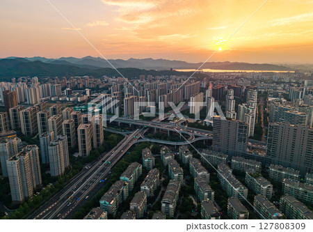 Urban aerial view of busy highway interchange in a modern city with flowing traffic during late afternoon Urban aerial view of busy highway interchange in a modern city with flowing traffic during late afternoon 127808309