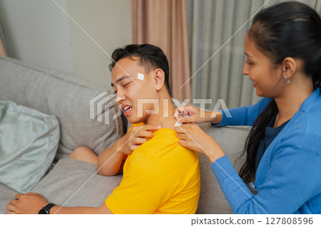 A Compassionate Friend Providing Assistance with a Bandage After an Accident at Home 127808596