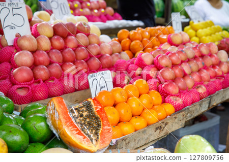 Apples, oranges, papaya, and avocados displayed at tropical fruit market stall with price tags in Philippines 127809756