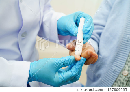 Asian doctor using digital glucose meter for check sample blood sugar level to treatment diabetes. Asian doctor using digital glucose meter for check sample blood sugar level to treatment diabetes. 127809965