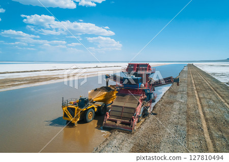 Heavy machinery works along the banks of Baskunchak Lake, actively extracting salt and transporting it into large trucks. Heavy machinery works along the banks of Baskunchak Lake, actively extracting salt and transporting it into large trucks. 127810494