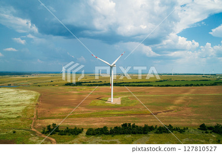 Wind turbines generate renewable energy in vast open landscape under a cloudy sky Wind turbines generate renewable energy in vast open landscape under a cloudy sky 127810527