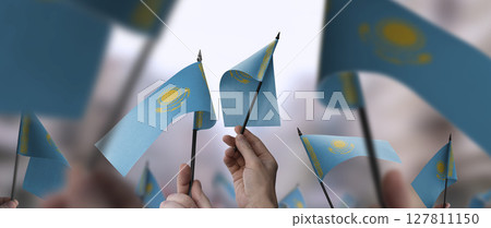 Kazakhstan flags in their hands on a blurred urban background 127811150