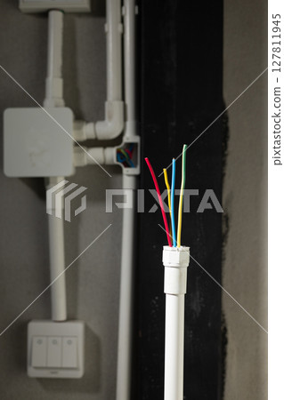 Electrician open cap of PVC inspection tee fitting on wall 127811945