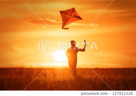 Boy with a kite at sunset Boy with a kite at sunset 127812220
