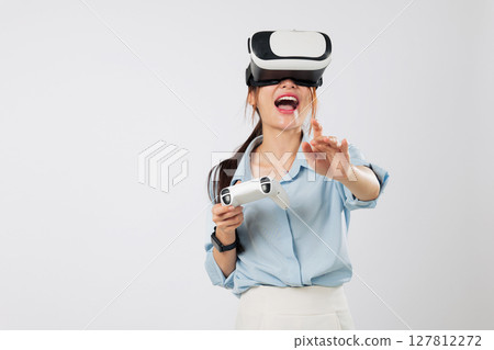 VR game fun with Young Asian woman pointing or touch at floating VR game interface using controller and enjoying the virtual world. isolated studio white background VR game fun with Young Asian woman pointing or touch at floating VR game interface using controller and enjoying the virtual world. isolated studio white background 127812272