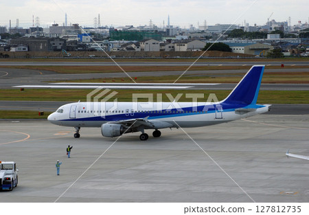 Ground staff waving to a departing plane 127812735