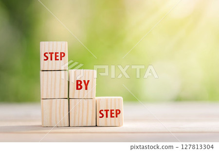 The word step by step on wooden cubes. Achievement or progress in business career. 127813304