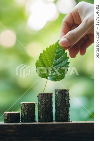 a hand placing a leaf on bar graph representing environmental progress 127814082