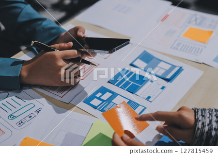 Group of young application developers analyzing uxui mobile app templates during a working meeting 127815459